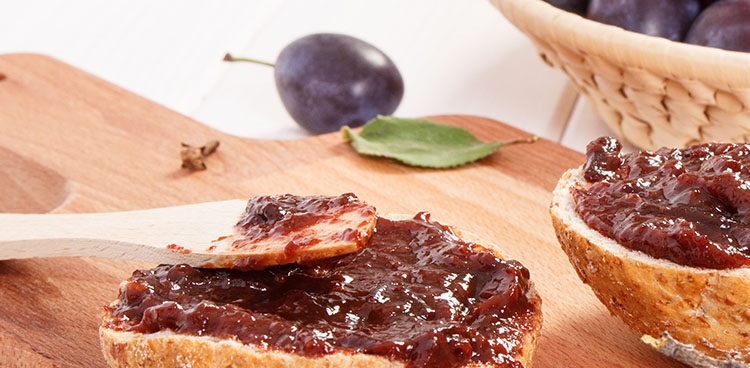 Wooden knife, sandwiches with plum marmalade or jam on wooden cutting board, concept of preparation delicious breakfast